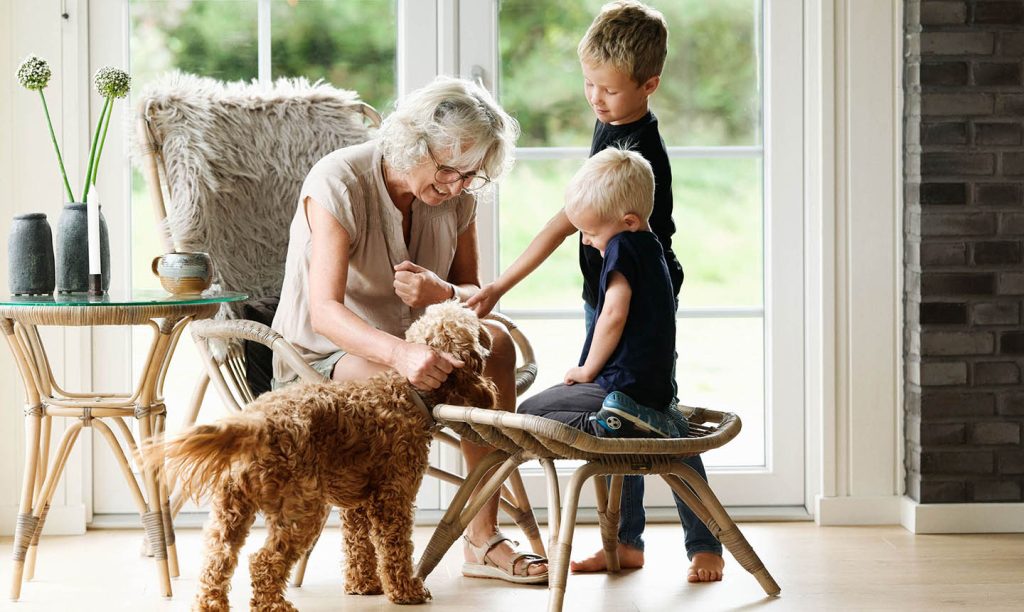 mormor og børnebørn sammen med deres hund i sommerhusets stue